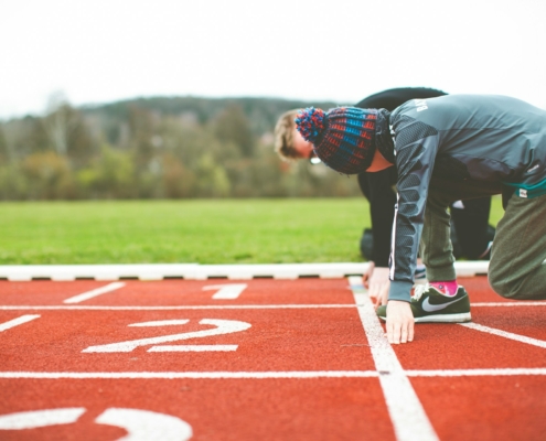 man in black and red plaid shirt and black pants standing on track field during daytime