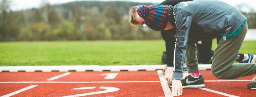 man in black and red plaid shirt and black pants standing on track field during daytime