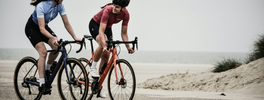 man and woman riding road bikes at the road near shore