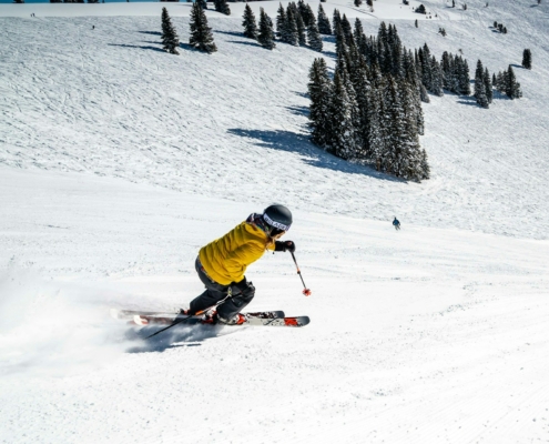 person in green jacket riding on red ski board on snow covered ground during daytime