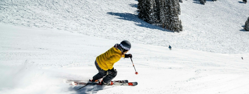 person in green jacket riding on red ski board on snow covered ground during daytime