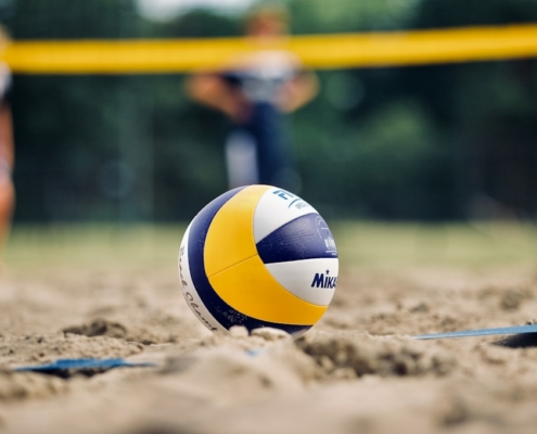 yellow and white volleyball on brown sand during daytime