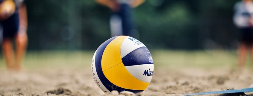 yellow and white volleyball on brown sand during daytime